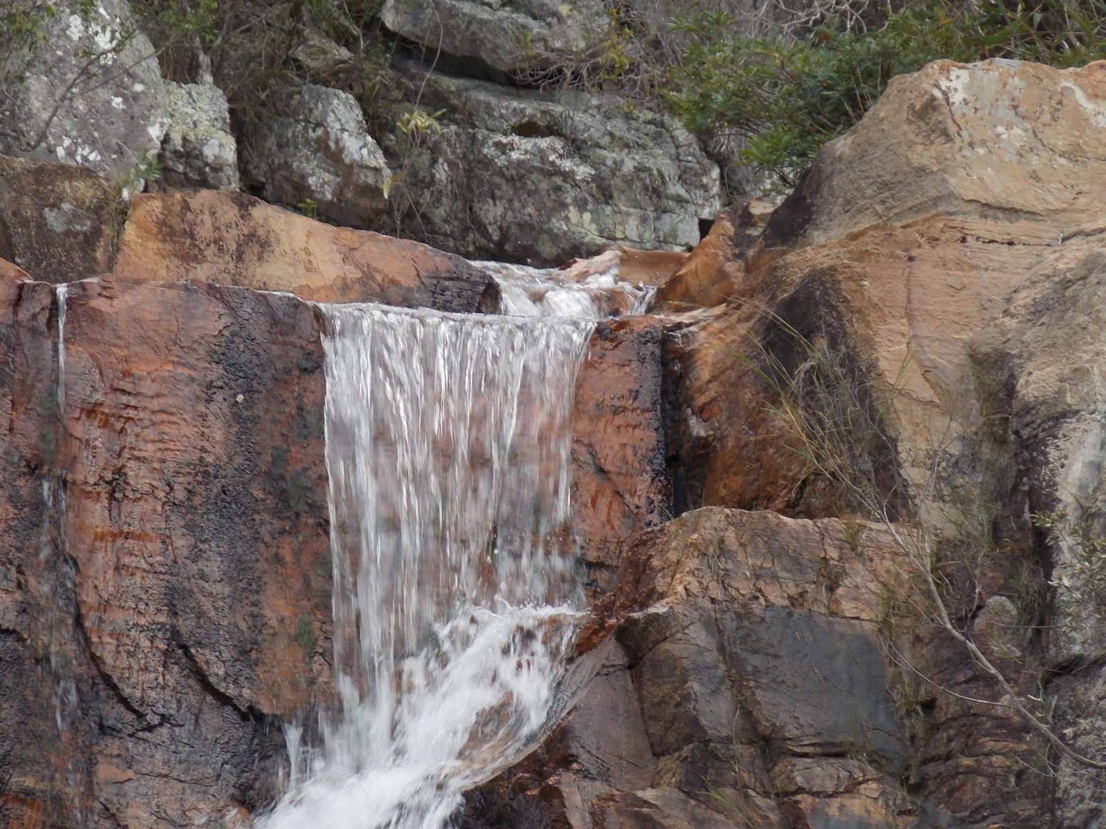 Guia em trilha com cachoeira ao fundo